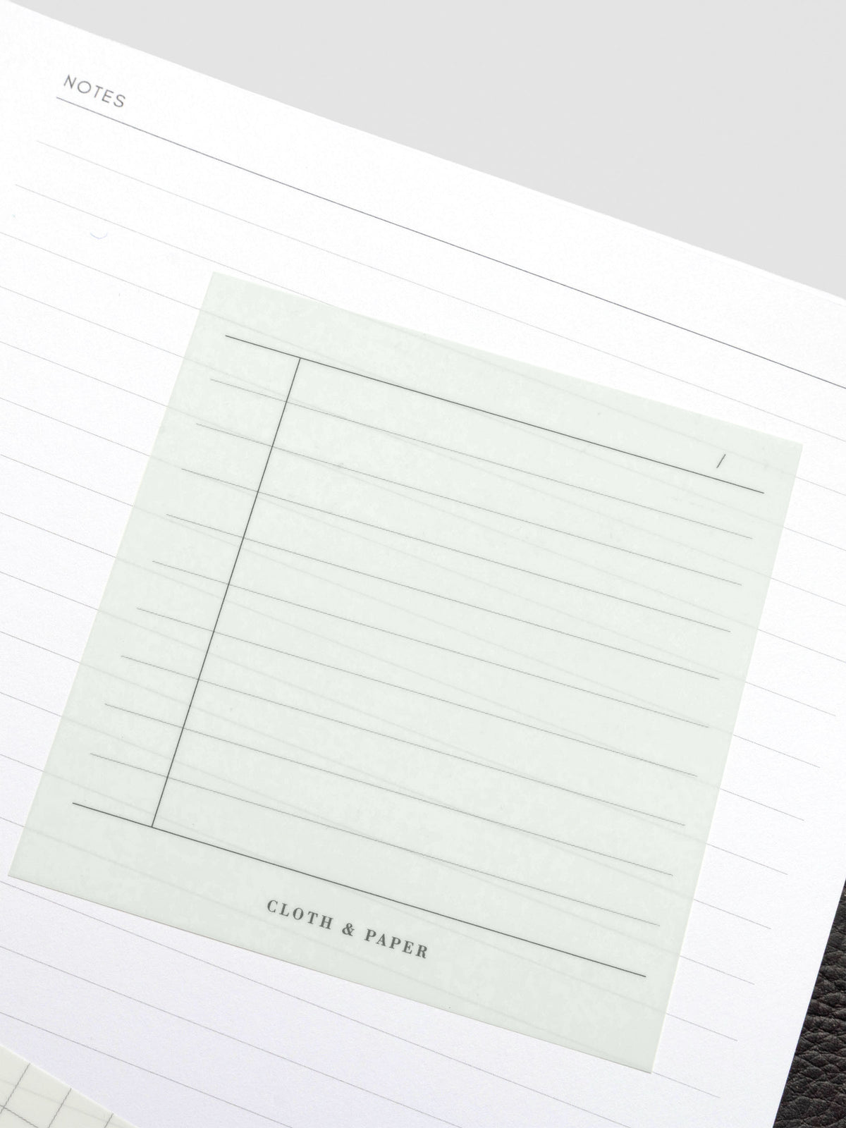 Transparent sticky note placed on a planner page, showing its see-through design over lined paper.