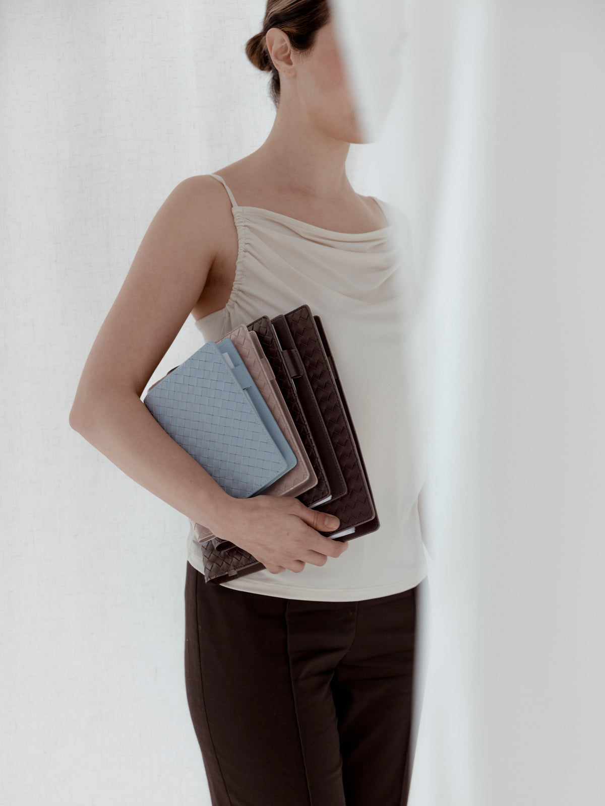 Woman holding a small, large, and HP Classic woven planner cover in the colors blue, beige, and brown.