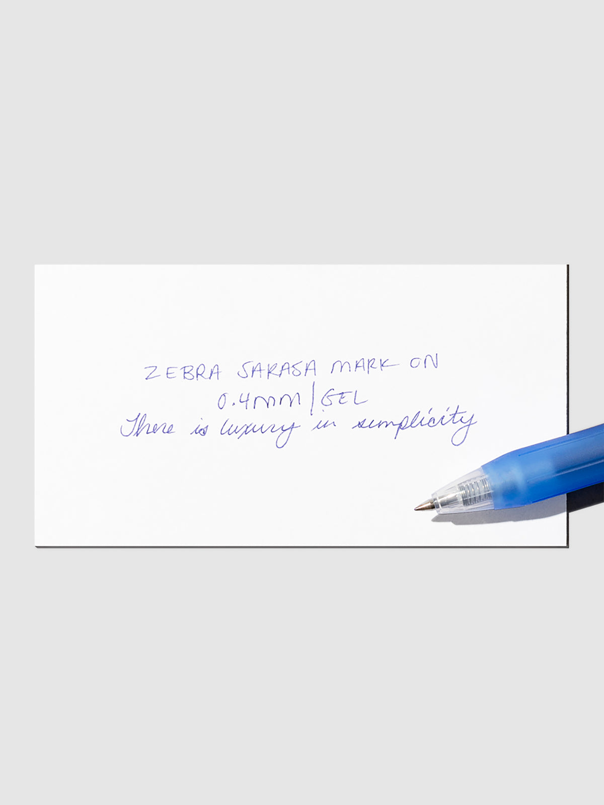 Pen in Blue resting on a pen test sheet displaying a writing sample detailing the pen's specs.