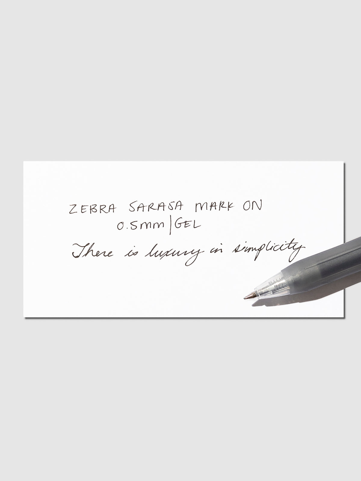 Pen in Black resting on a pen test sheet displaying a writing sample detailing the pen's specs.