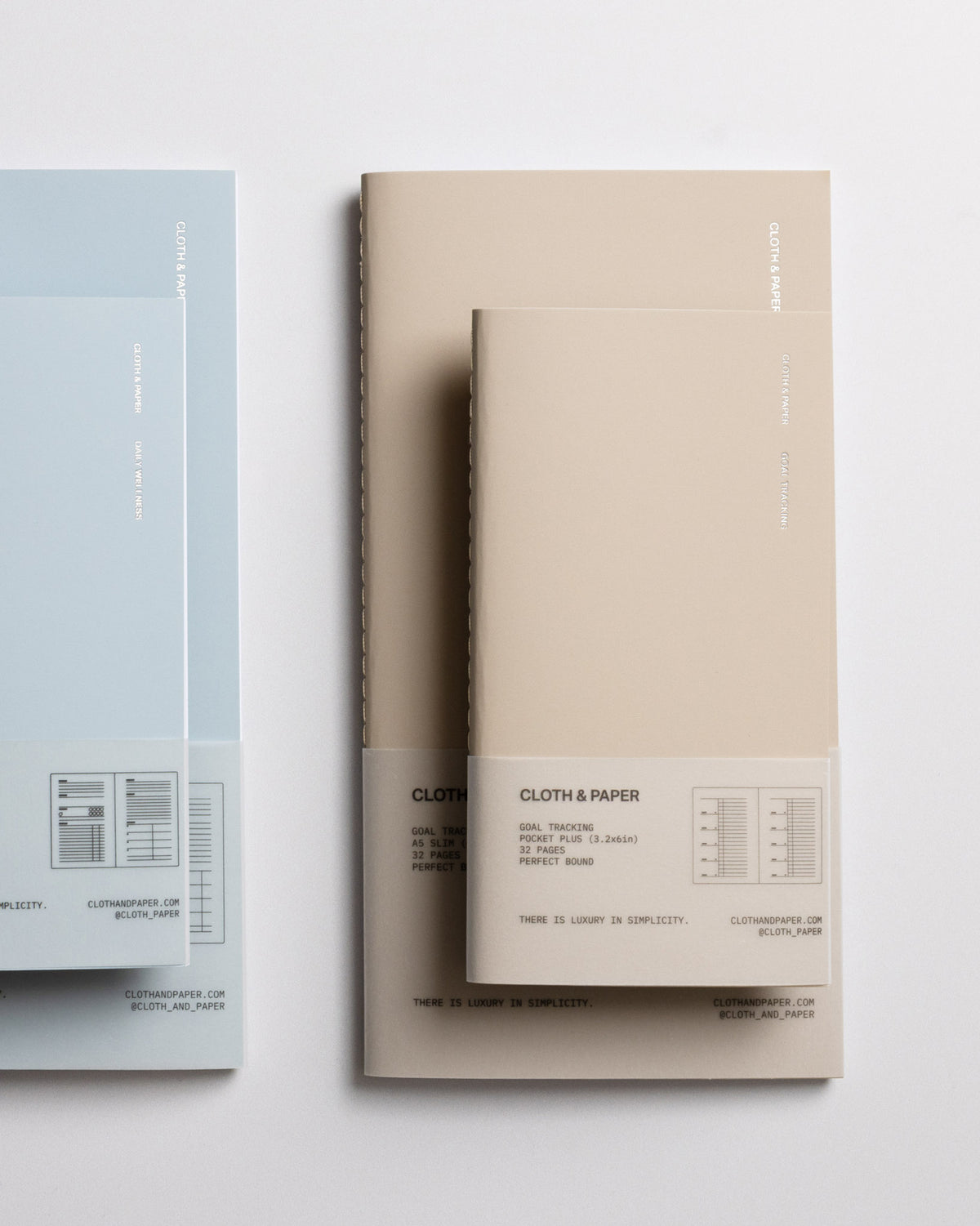 Pocket Plus travel notebook laying on top of an A5 Slim travel notebook against a grey background.