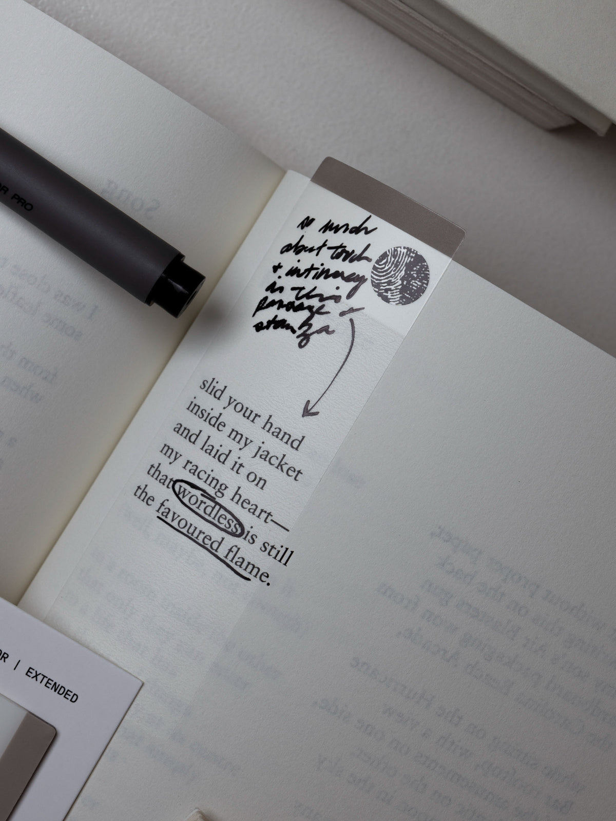 Extended page flag affixed to an open book page with handwritten notes.