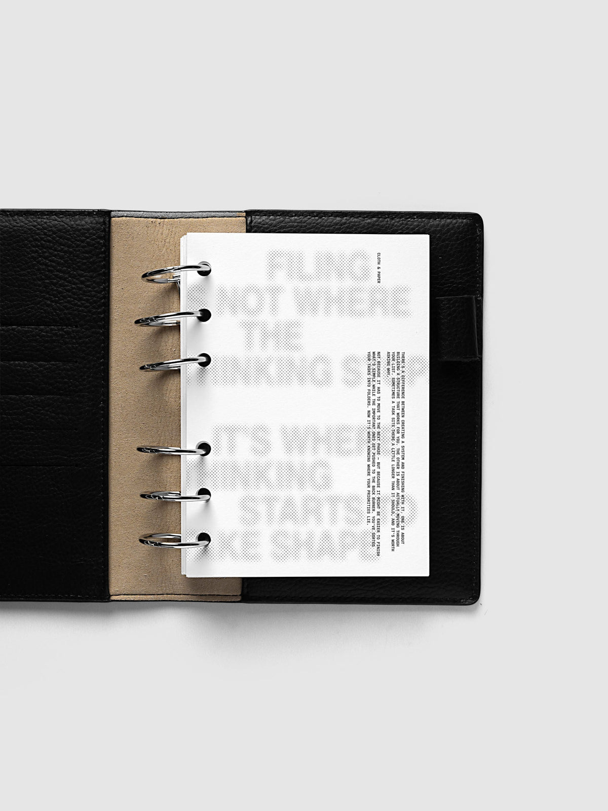 Halftone Planner Dashboard, A6 6-Ring Punch, dashboard on the rings of an open black leather planner, the grey halftone headline across the page