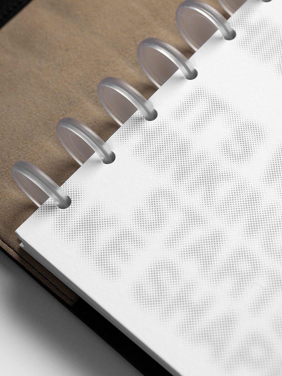Halftone Planner Dashboard, Half Letter 8-Disc Punch, close-up of the discs over a kraft panel, the halftone letters fading toward the edge