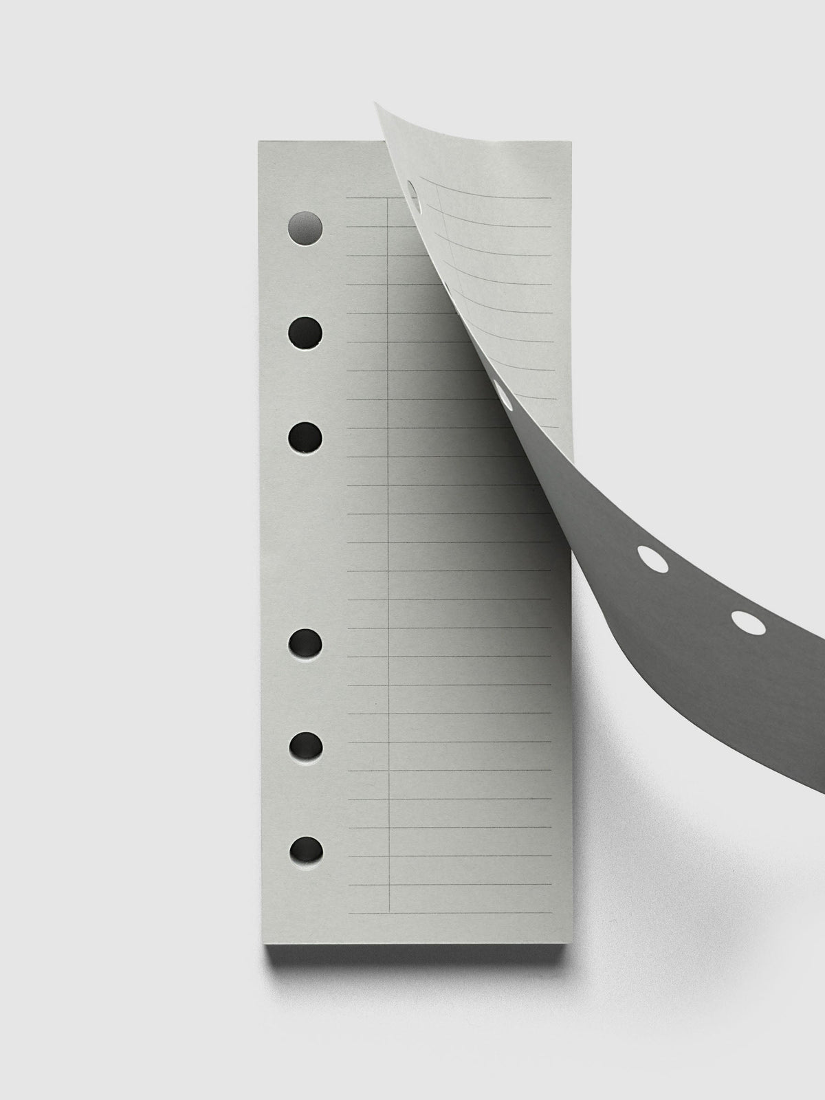System Punch Pad, A6 6-Ring Punch, top sheet lifting away from the pad, round ring holes showing along both the sheet and the pad