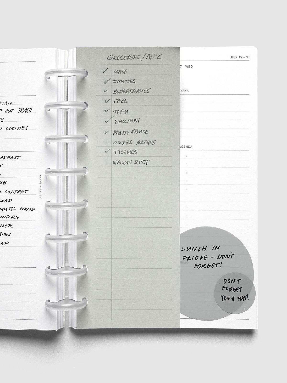 System Punch Pad, Half Letter 8-Disc Punch, sheet clipped onto frosted discs over an open weekly spread, a handwritten grocery list checked off down the page
