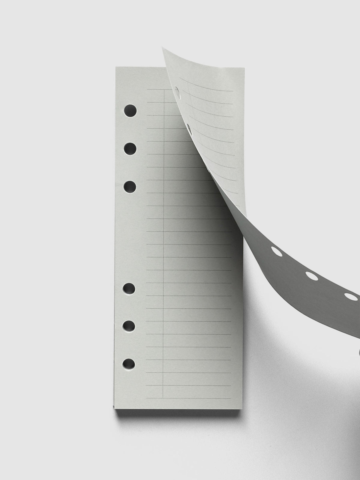 System Punch Pad, Personal 6-Ring Punch, top sheet lifting away from the pad, round ring holes showing along both the sheet and the pad