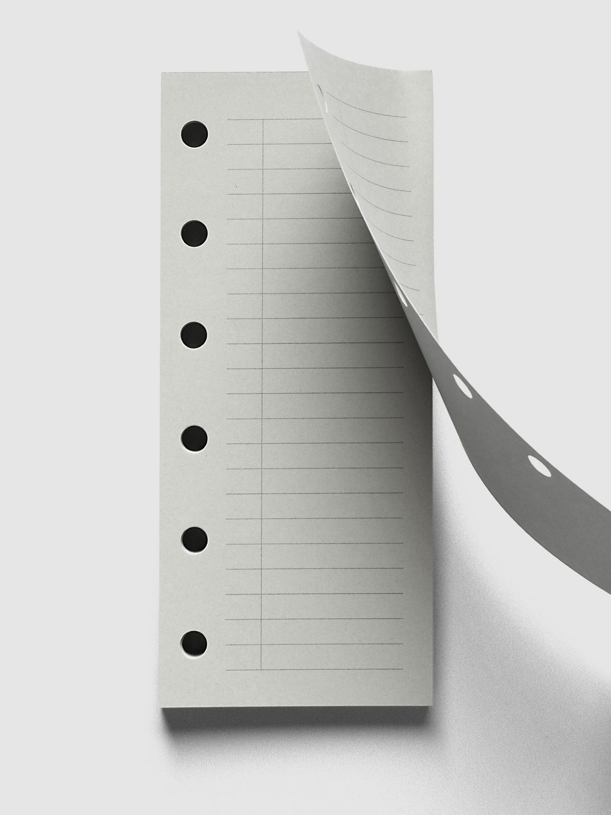 System Punch Pad, Pocket 6-Ring Punch, top sheet lifting away from the pad, round ring holes showing along both the sheet and the pad