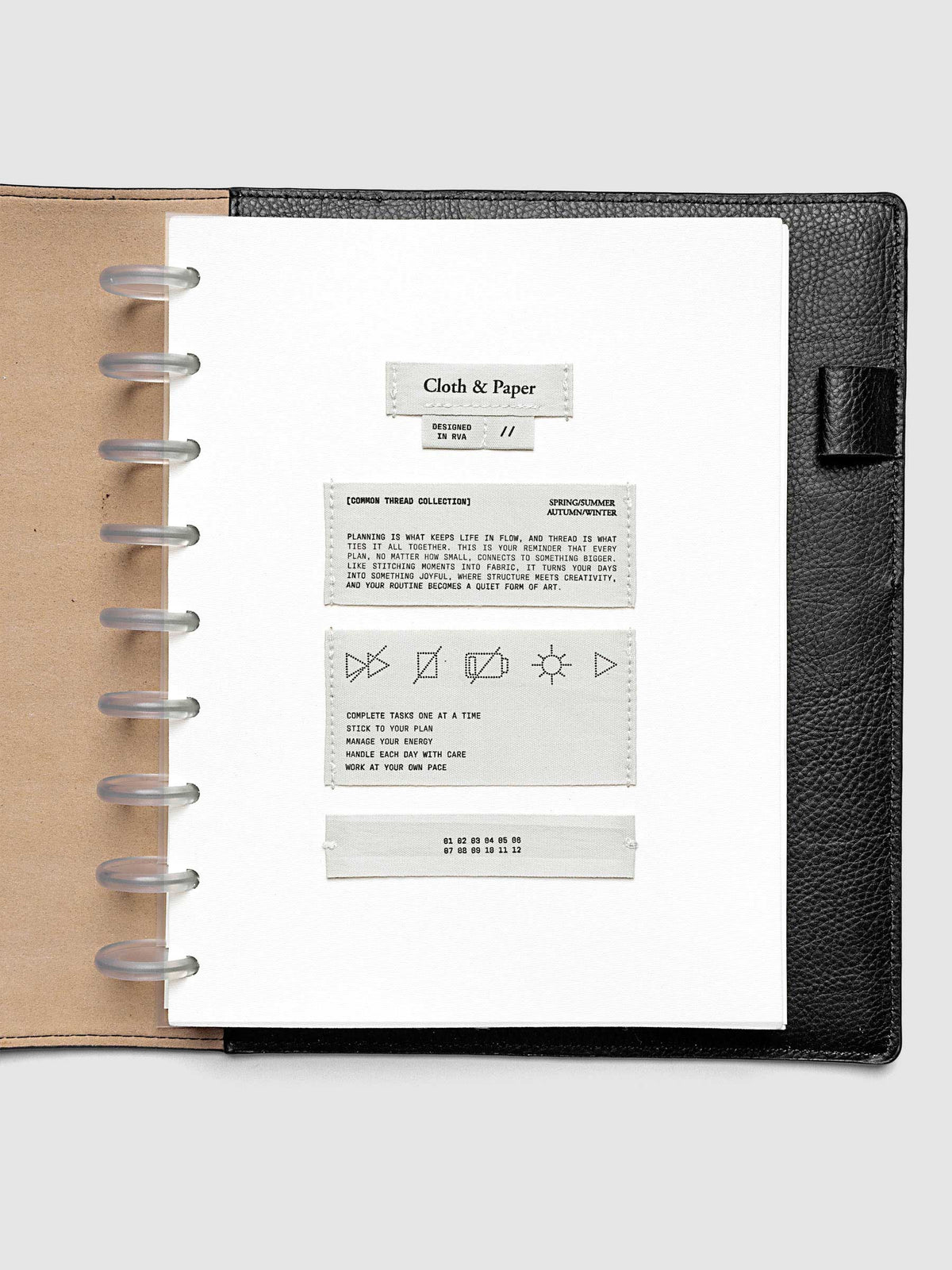 Sewn Tags Planner Dashboard pre-punched for discbound planners in size HP Classic shown in a black leather folio.