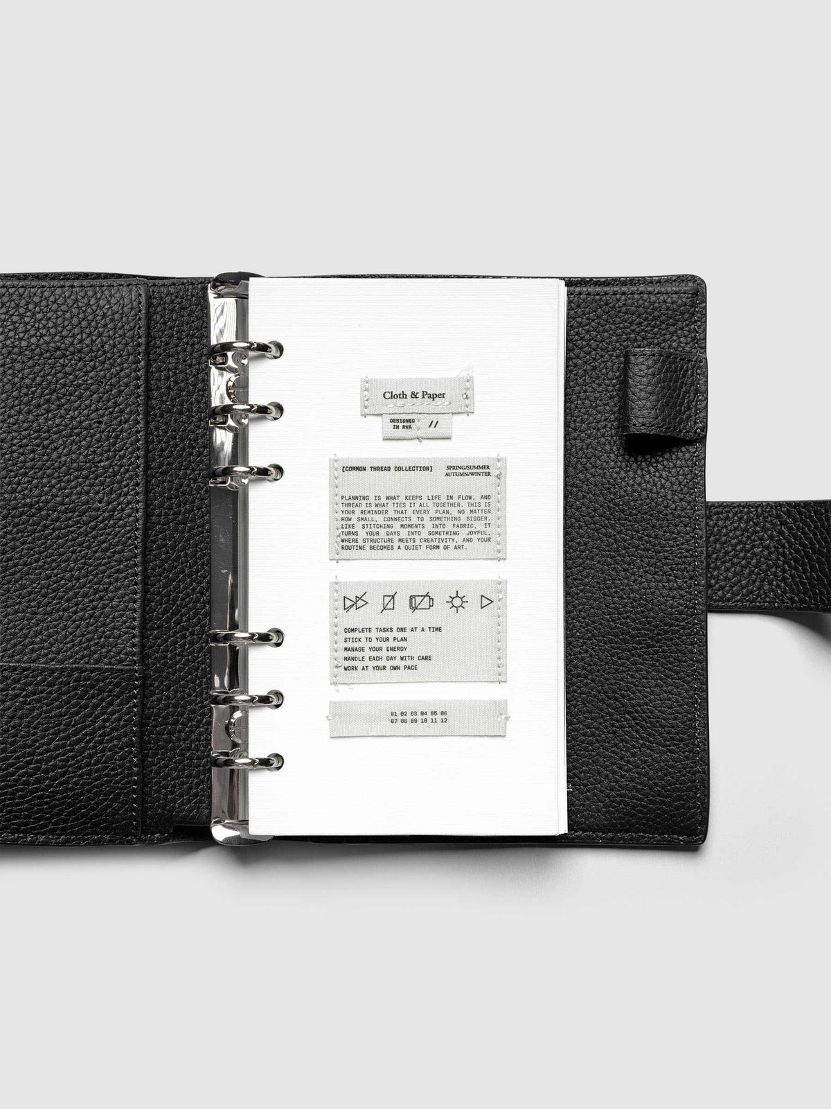 Sewn Tags Planner Dashboard pre-punched for 6-ring planners in size Personal shown in a black leather agenda.