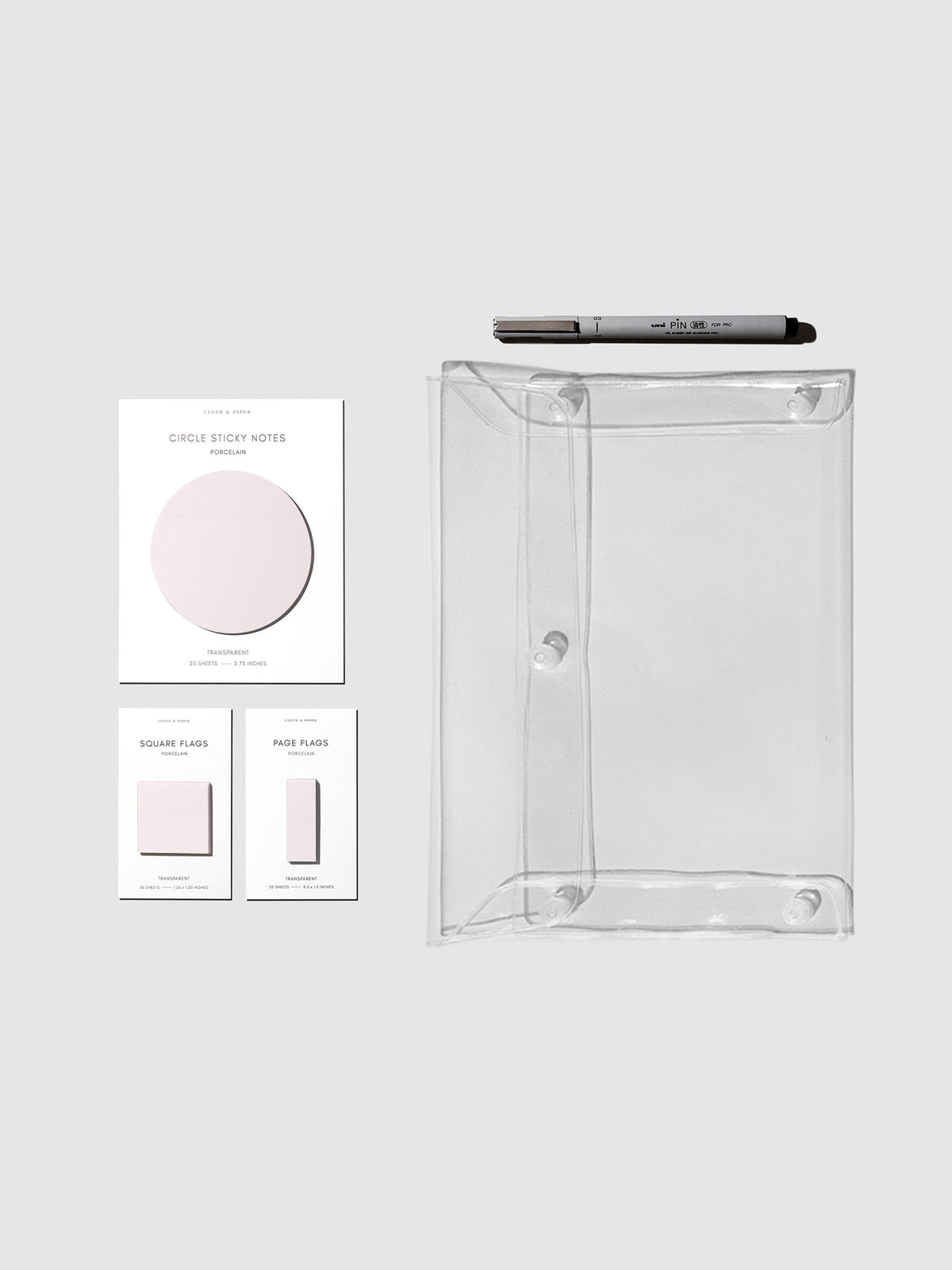 Matching set of circle sticky notes, page flags, and square page flags positioned next to a Uni Pin Marking Pen and Essentials Clear pouch. Sticky note color is Porcelain.