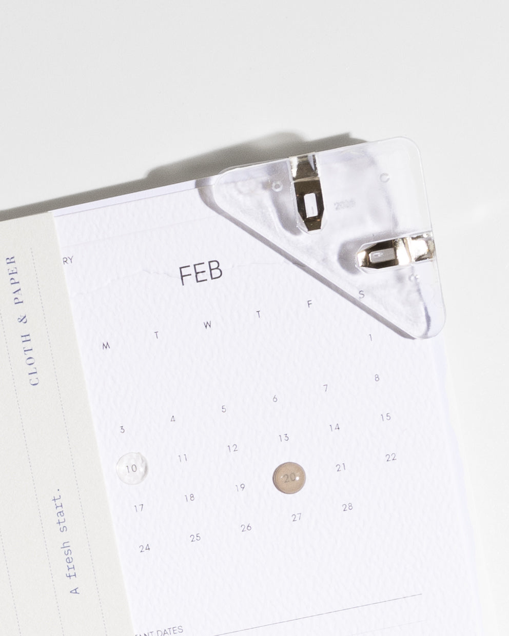 Circular raised stickers shown in clear and Cortado (light brown) in use on a pocket calendar.