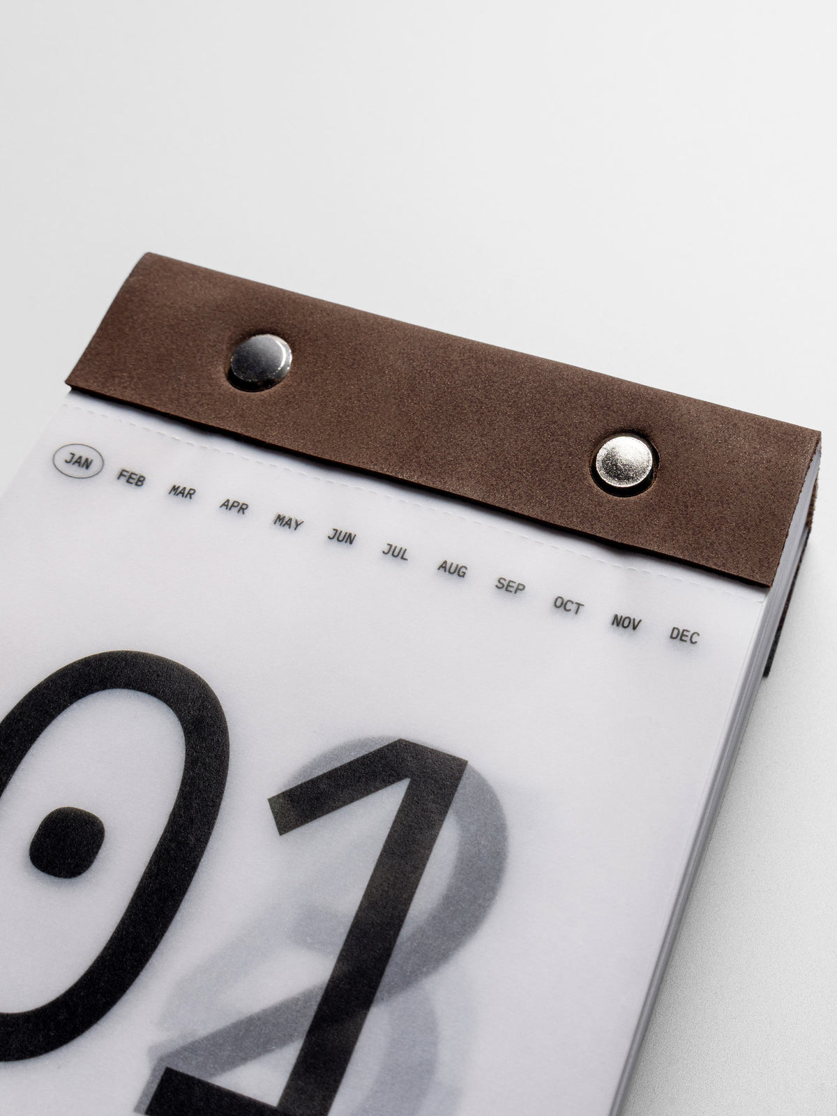 Close up of the suede and metal pin binding on the 2026 Today Tear Off Pad. Abbreviated months header at the top with the current month indicated by a circle.