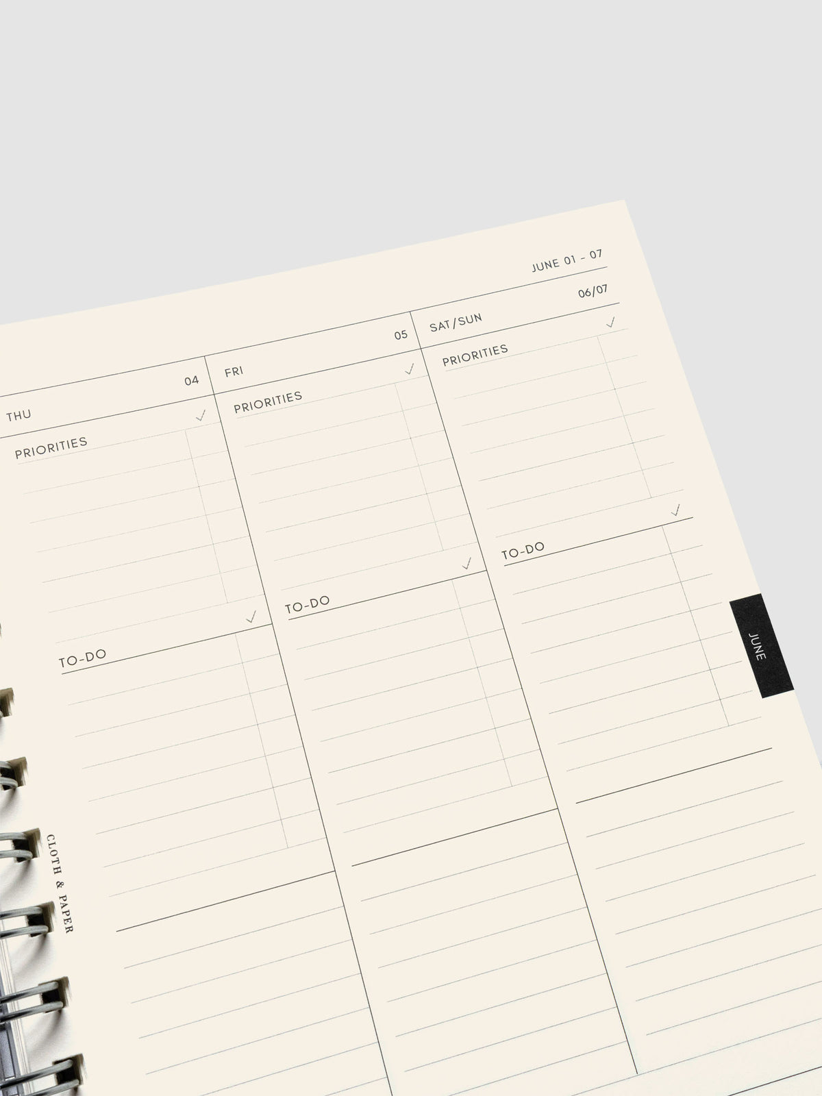 Close up of a weekly task layout page on cream paper showing daily sections for priorities and to-dos.