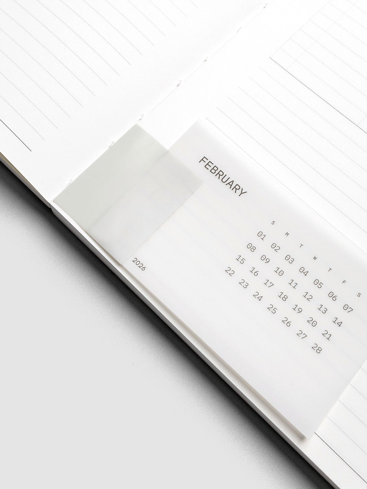Unpunched system punch sticker with clear calendar card attached shown inside a perfect bound notebook.