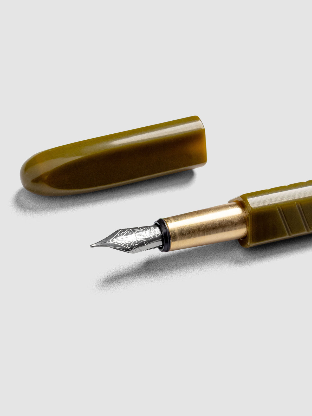 Kolo Tino Fountain Pen in the color Acrylic Wasabi, a warm green barrel with brass accents and a silver medium nib shown with cap off.
