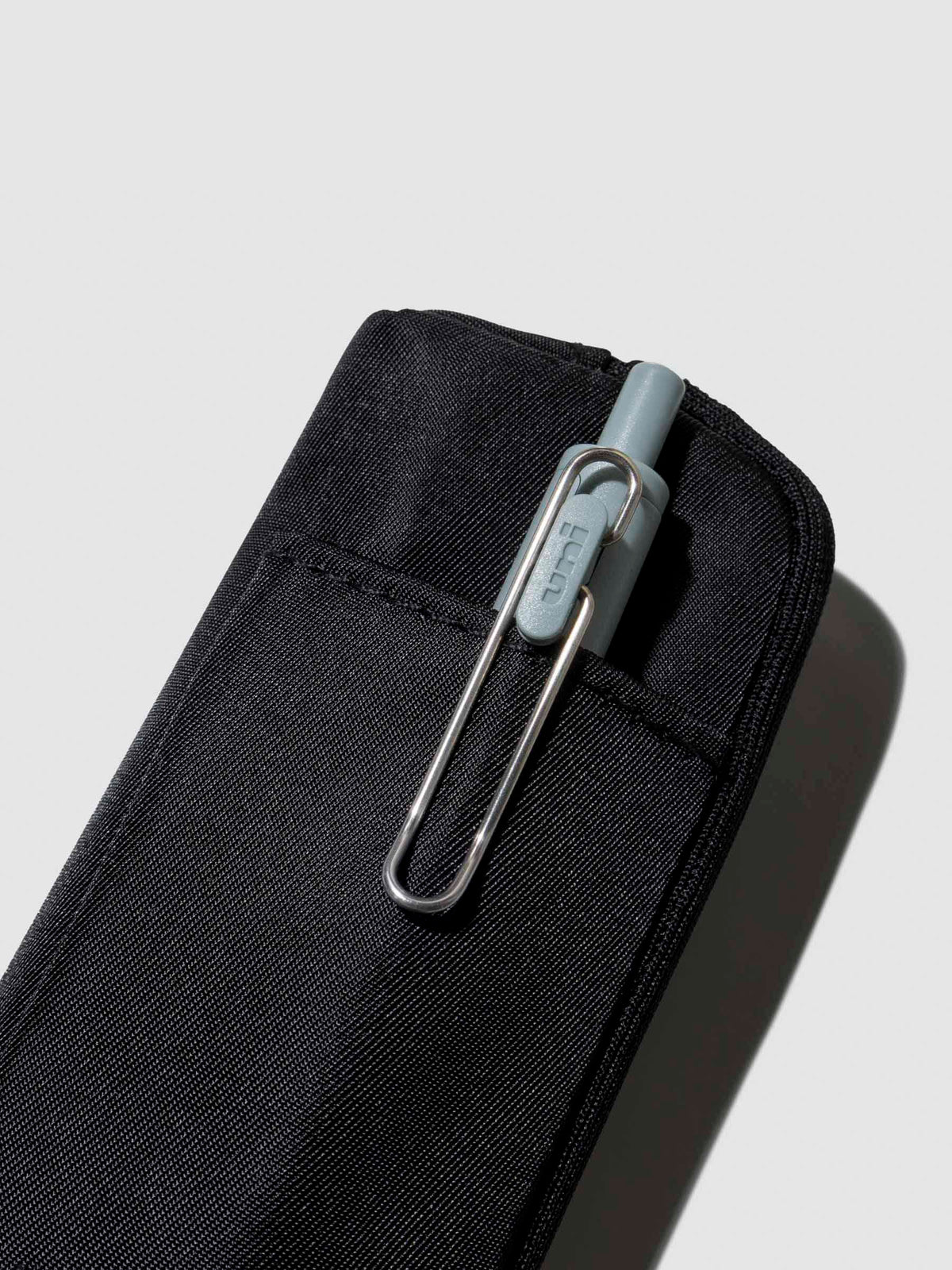 Uni Ball One pen displayed inside the external pocket of a notebook pouch. Color shown is Avant Garde.