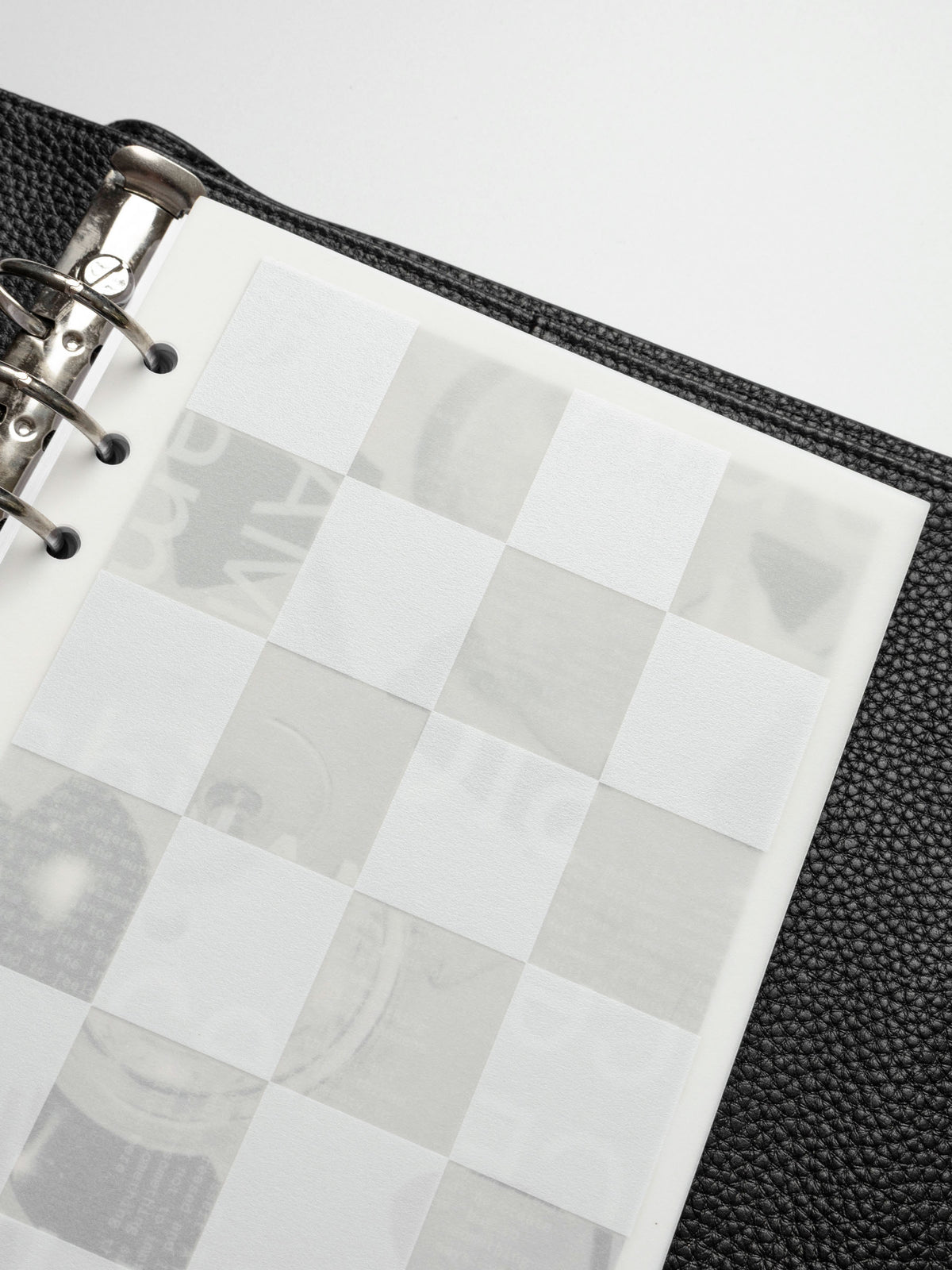 A close-up of the Ambiance Planner Dashboard checkered layer in an A5 planner, highlighting the frosted translucent material and white square pattern.