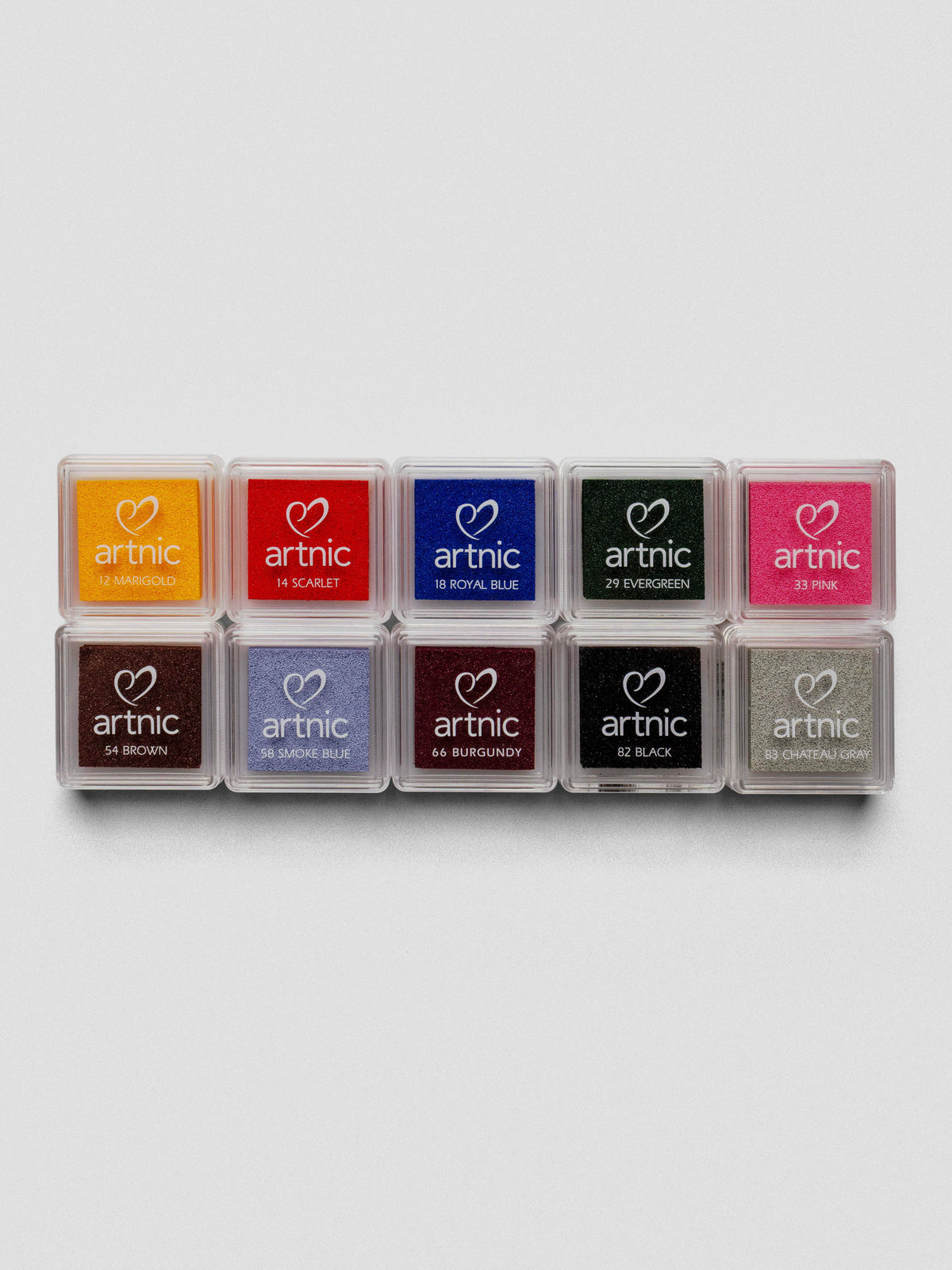 Row of ten Artnic Stamp Ink Pads in assorted colors, arranged side by side with clear lids displaying the color names.