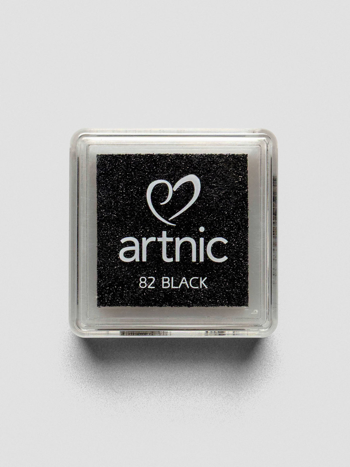 Top-down view of a closed Artnic stamp ink pad in black, with the color name and logo printed on the clear lid.