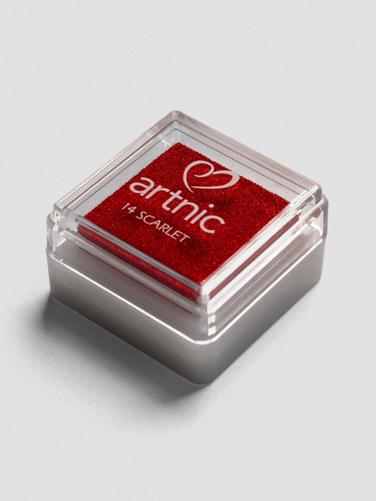Red Artnic ink pad with clear lid, angled view showing its stackable design.