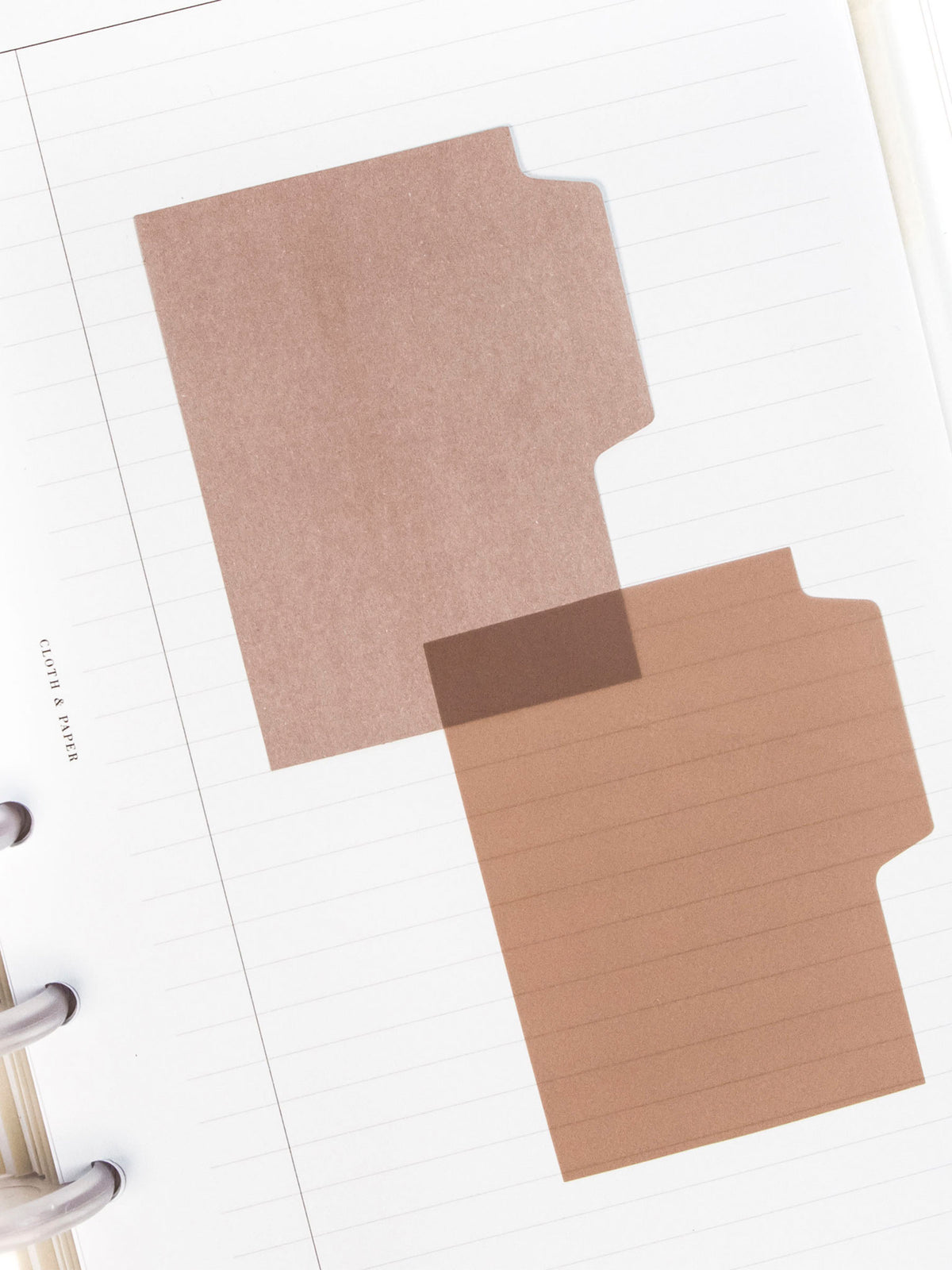 Blank Tab Sticky Note Set, Chatoyant, Cloth and Paper. One matte and one transparent sticky note from the set placed on a task insert. The transparent sticky note is layered over the bottom right corner of the matte sticky note.