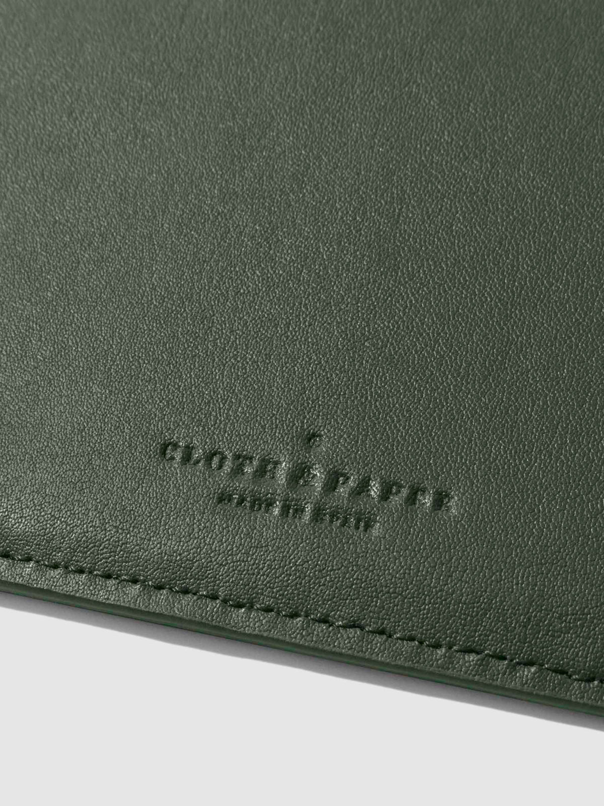 Closeup of valley green folio's textured vegan leather and stamped Cloth and Paper logo.