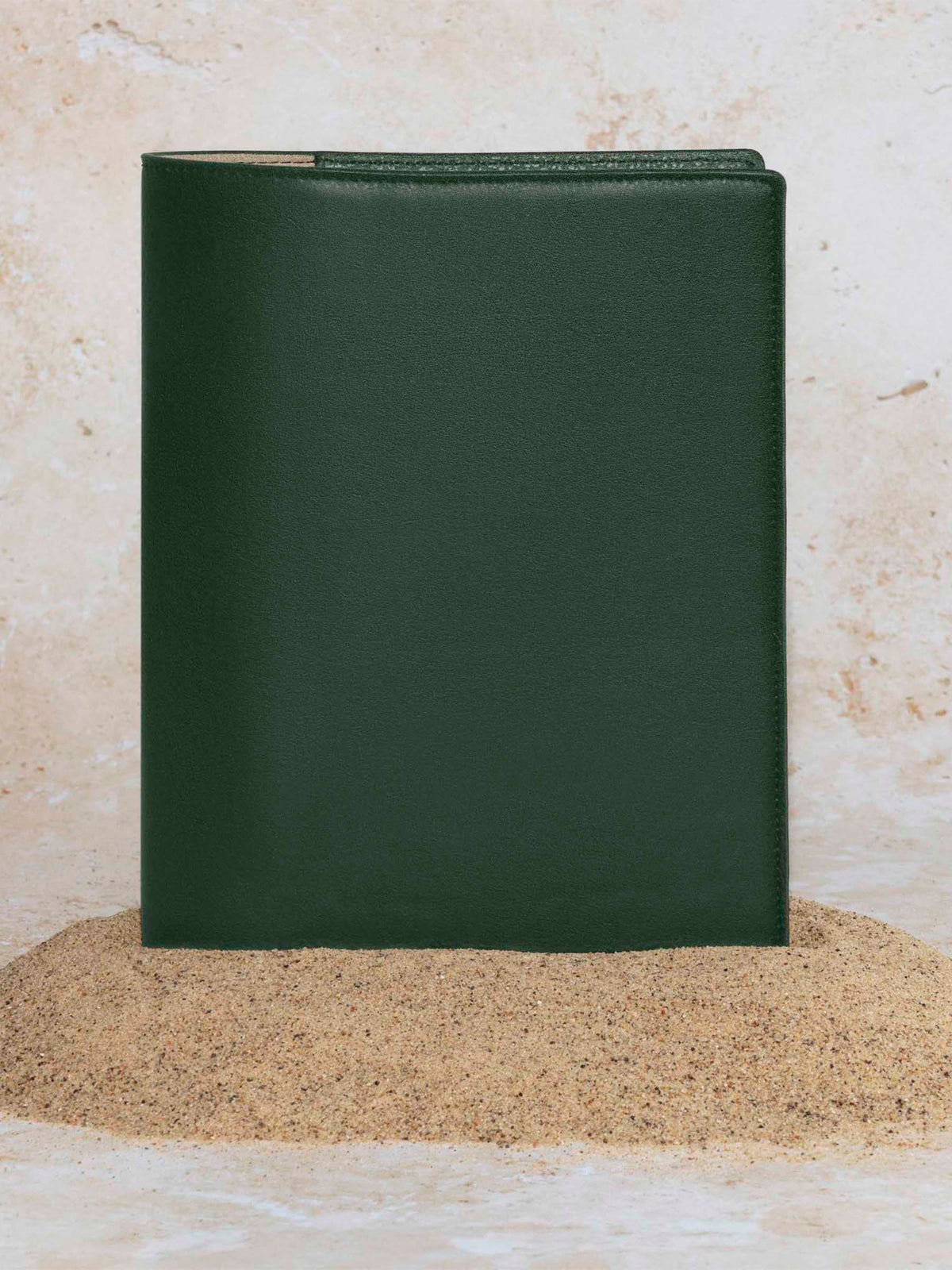 Folio displayed on a textured tan background, placed in a pile of sand. Color pictured is valley green.
