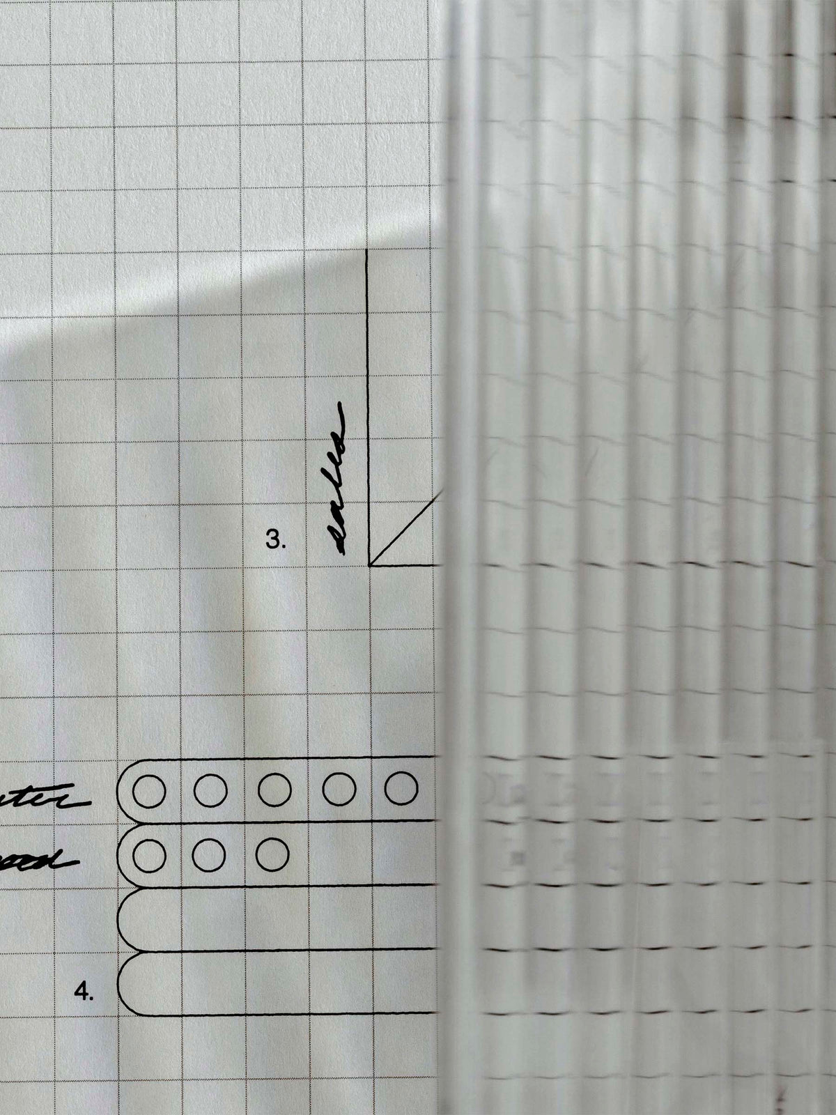 Photo focusing on the texture and light reflections caused by the dashboard on a piece of graph paper.