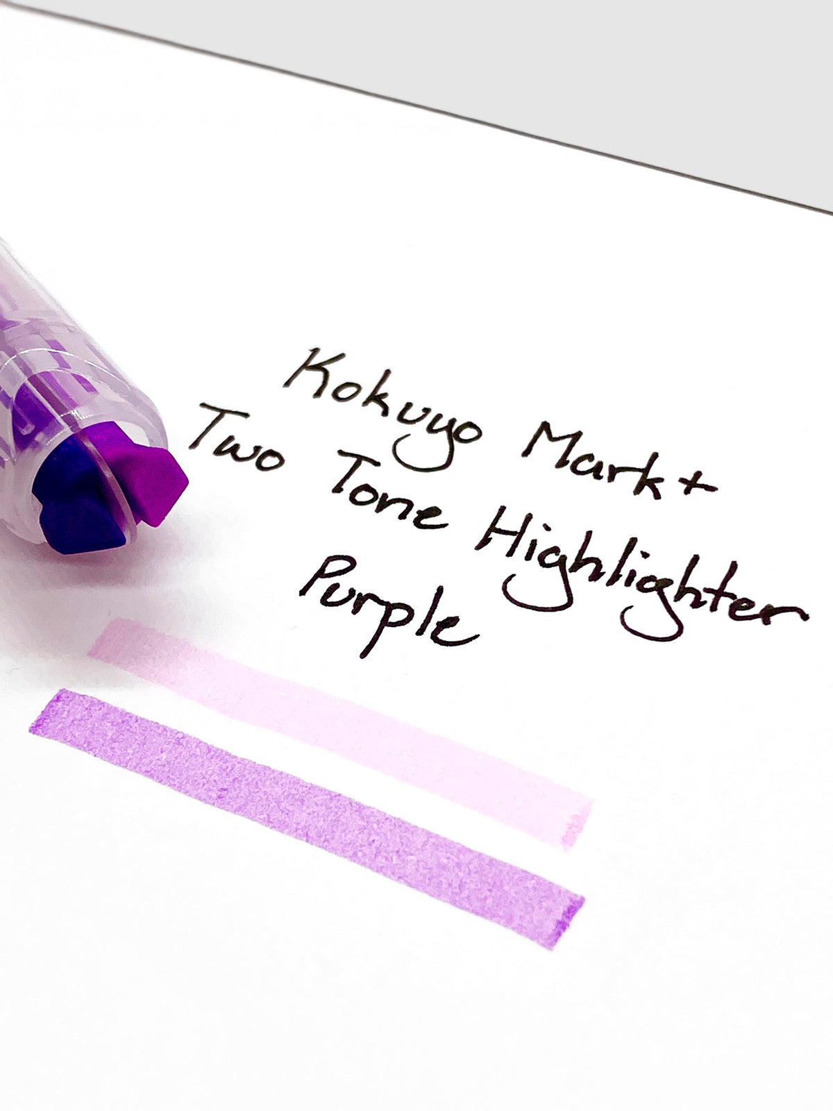 Close up on the dual tip nib of the highlighter. The highlighter is resting on a piece of paper displaying a writing sample.
