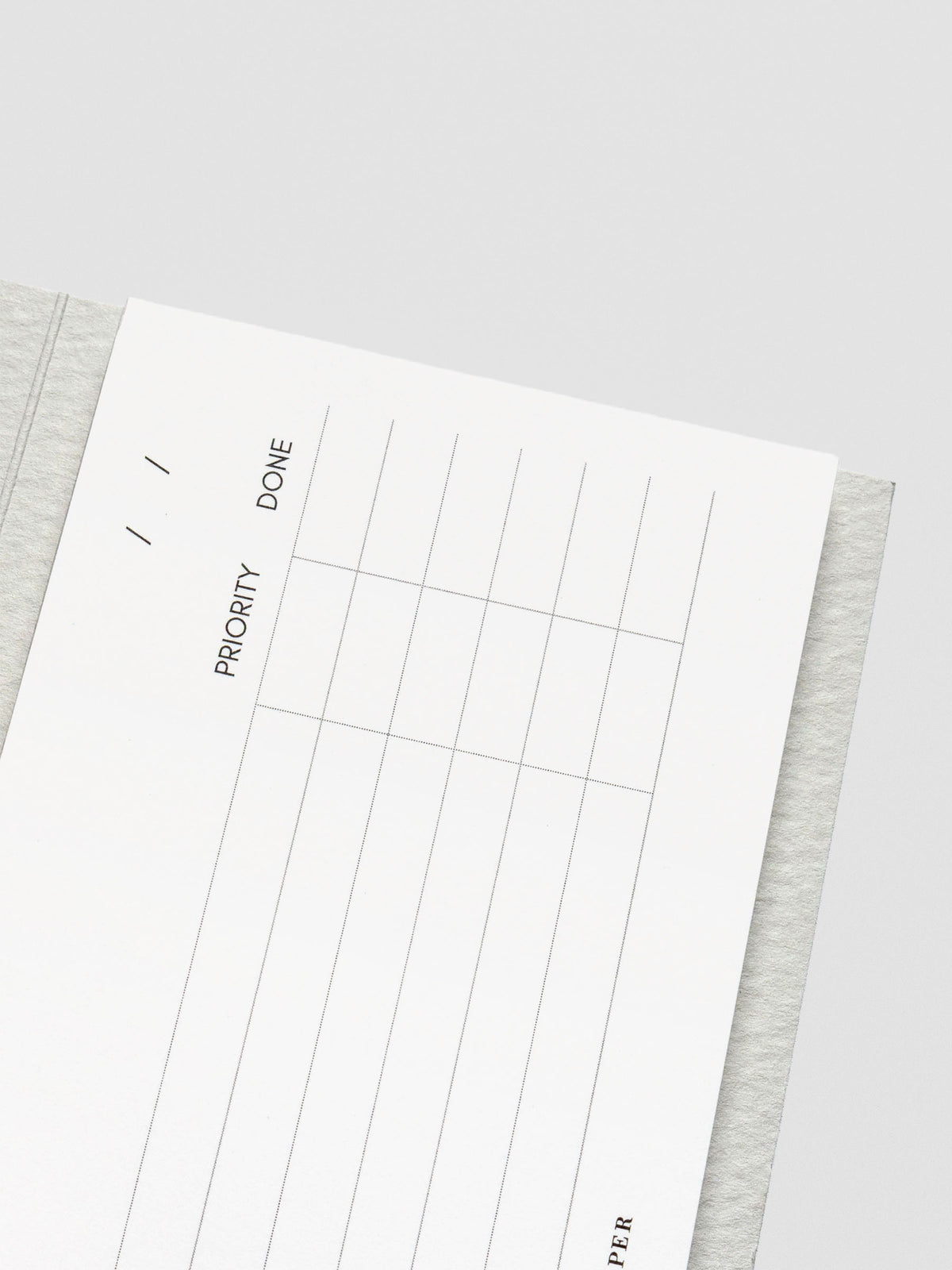 Close-up of the top portion of the notepad showing date lines and priority and done checkboxes printed in fine black ink on white paper.