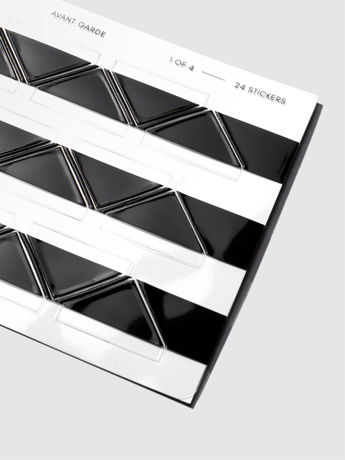 Closeup of black photo corners in their packaging displayed on a neutral background.