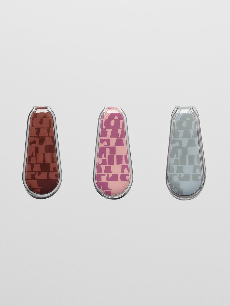 Three patterned magnetic bookmarks in unique colors including red, pink, and blue on a neutral background.