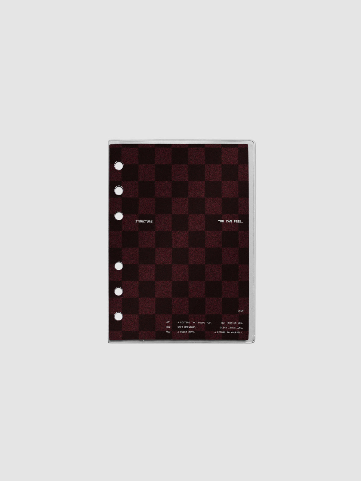 A6 sized velvet checkered dashboard in the color Bordeaux in between two crystal clear plastic planner covers with text printed on the cover on the theme of structure and routines.