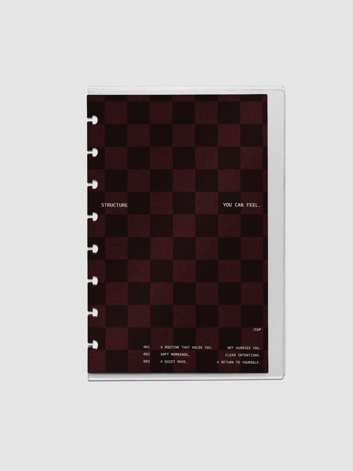 Half Letter sized velvet checkered dashboard in the color Bordeaux in between two crystal clear plastic planner covers with text printed on the cover on the theme of structure and routines.