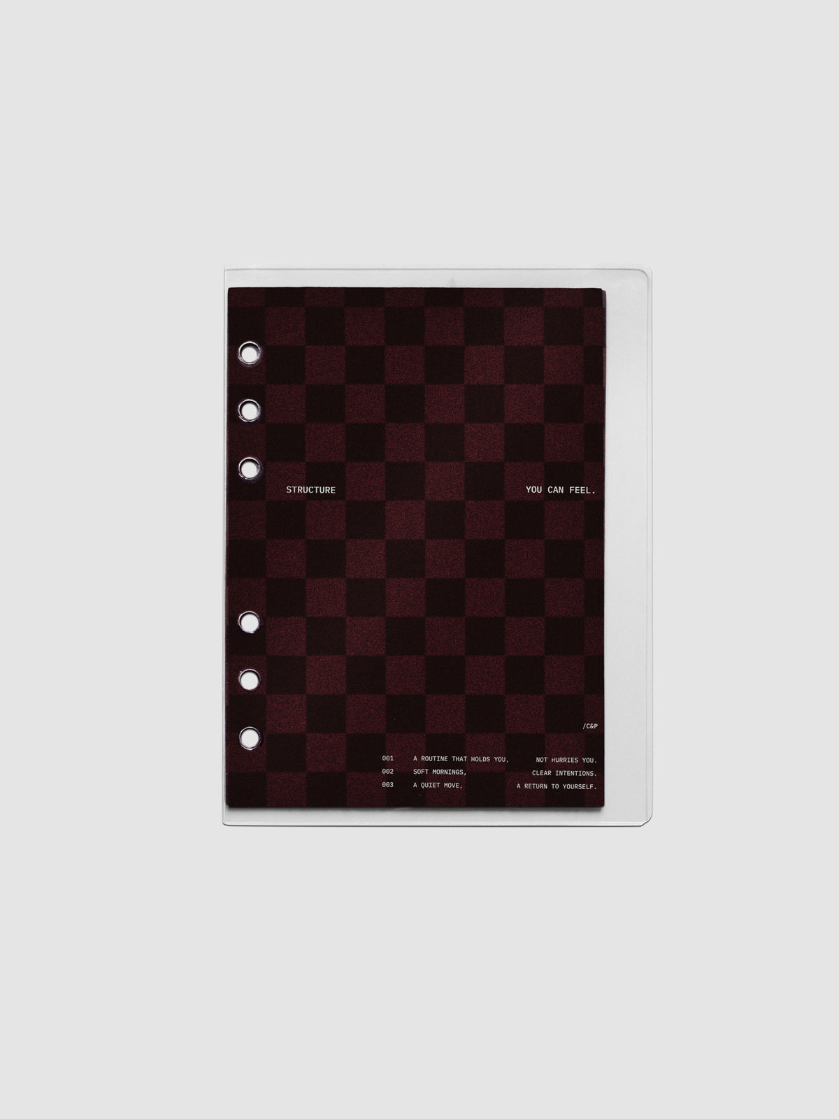 Personal Wide sized velvet checkered dashboard in the color Bordeaux in between two crystal clear plastic planner covers with text printed on the cover on the theme of structure and routines.