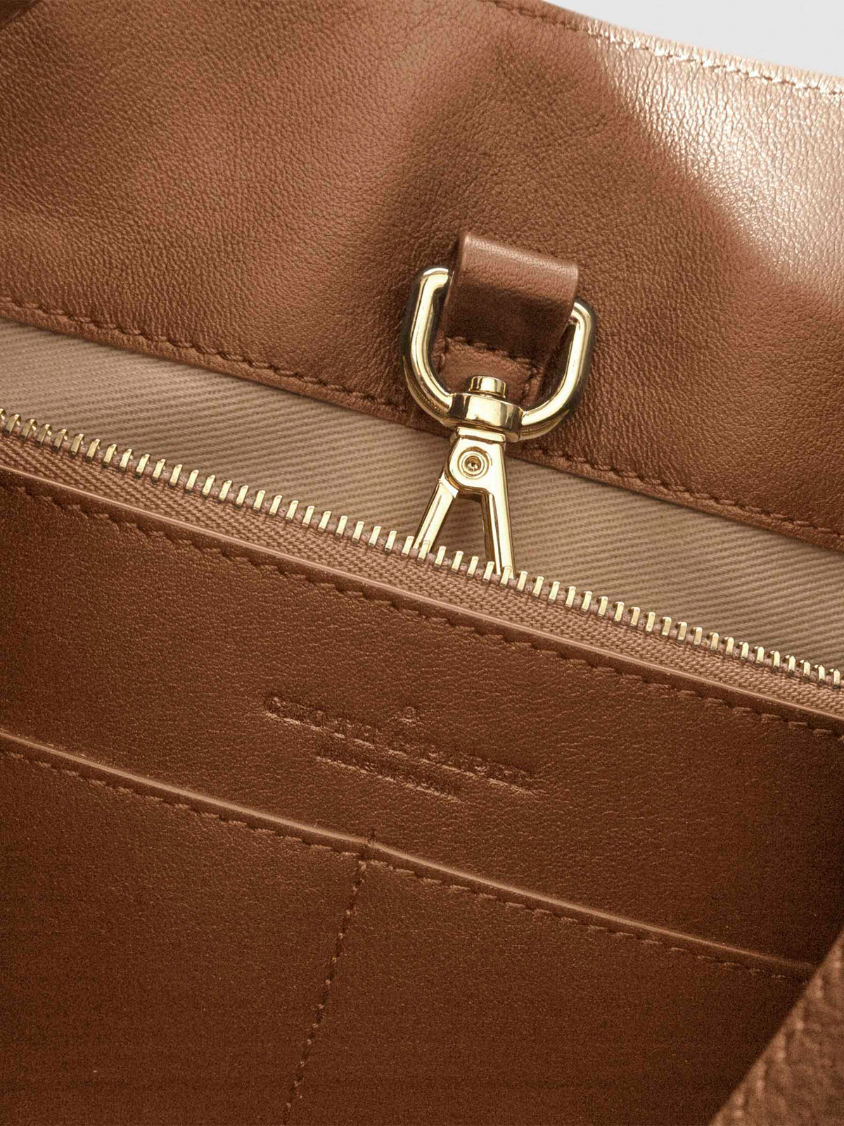 Top down view of bag showcasing its gold hardware. It secures the bag shut. Color shown is Alhambra.