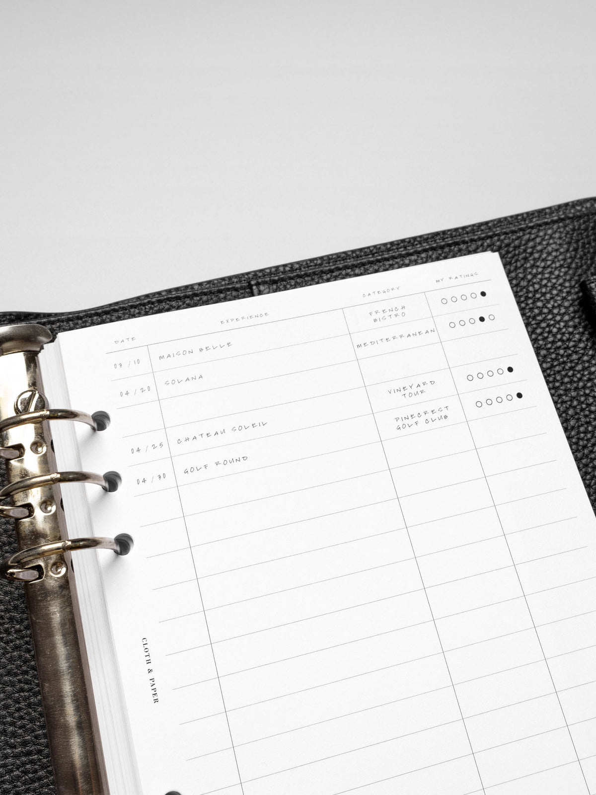 Close-up angled view of the A5 Tracker Planner Insert, highlighting handwritten experiences and the structured rating system.