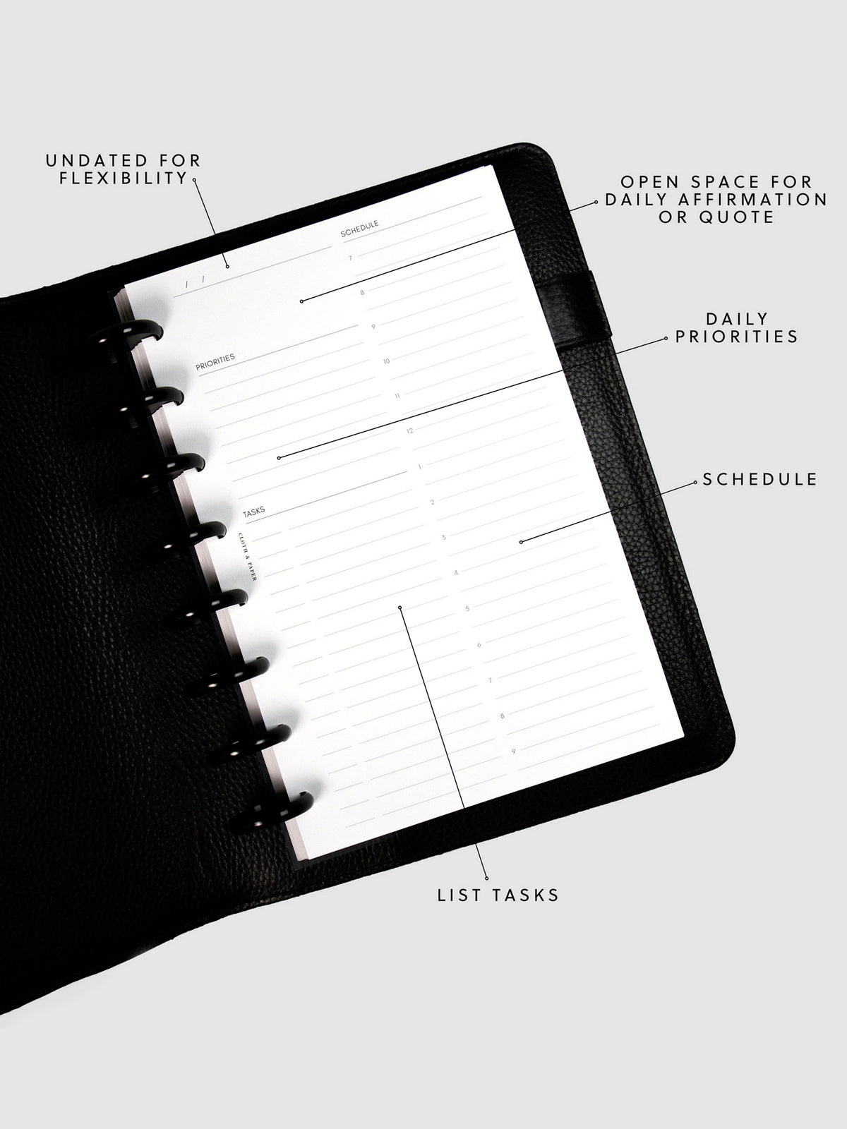 Undated Daily Planner Inserts in a black discbound planner tilted slightly to the left. Annotations for the sections include: Undated for Flexibility, Open Space for Daily Affirmation or Quote, Daily Priorities, Schedule and List Tasks