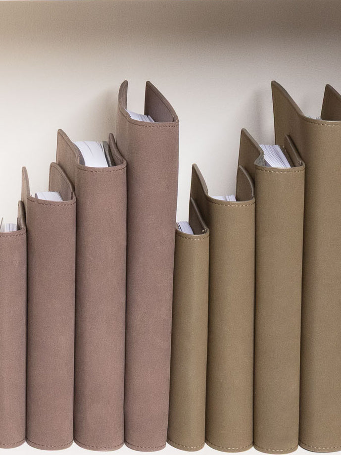 Various sizes of Vegan Leather Folios on a white bookshelf.